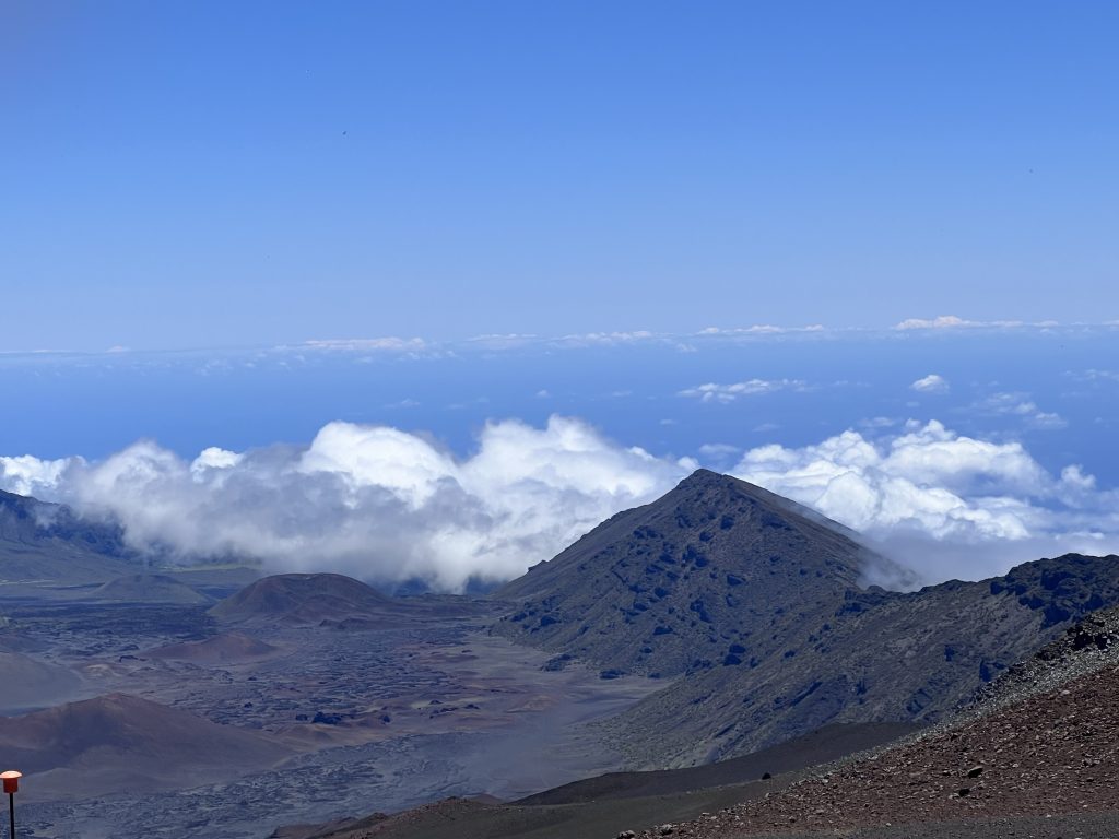 top of the Haleakala volcano and crater with clouds just beneath its peak.